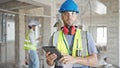 Two men builders using touchpad at construction site Royalty Free Stock Photo