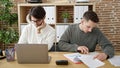 Two men business partners using laptop writing on document working at office Royalty Free Stock Photo