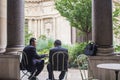 Two men in business suits confer at a cafe table in the courtyard of the Petit Palais, Paris