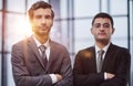 Two serious young businessmen standing with arms crossed in office Royalty Free Stock Photo