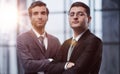 Two serious young businessmen standing with arms crossed in office Royalty Free Stock Photo