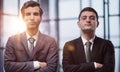 Two serious young businessmen standing with arms crossed in office Royalty Free Stock Photo