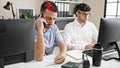 Two men business workers using computer talking on smartphone at office Royalty Free Stock Photo