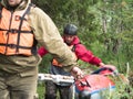 Two men carry inflatable catamaran t