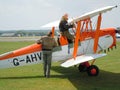 Two men climbing aboard historic biplane aircraft
