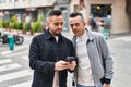 Two men couple using smartphone with relaxed expression at street Royalty Free Stock Photo