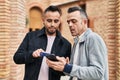 Two men couple using smartphone with relaxed expression at street Royalty Free Stock Photo