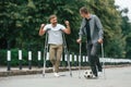 Two men with crutches is outdoors on the road. With a soccer ball Royalty Free Stock Photo
