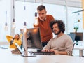 Two men discuss a project while looking at a computer monitor in a modern office Royalty Free Stock Photo