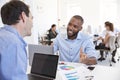 Two men discussing business in a busy office Royalty Free Stock Photo