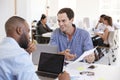 Two men discussing business documents in a busy office Royalty Free Stock Photo