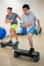 Two men doing step aerobic exercise with dumbbell on stepper Royalty Free Stock Photo