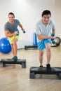 Two men doing step aerobic exercise with dumbbell on stepper Royalty Free Stock Photo