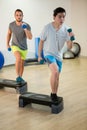 Two men doing step aerobic exercise with dumbbell on stepper Royalty Free Stock Photo