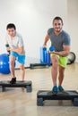 Two men doing step aerobic exercise with dumbbell on stepper Royalty Free Stock Photo