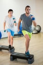 Two men doing step aerobic exercise with dumbbell on stepper Royalty Free Stock Photo