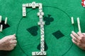 Two men in a domino game, pieces arranged in the center of the table