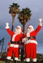 Two men dressed as Santa Clause under palm trees Royalty Free Stock Photo