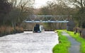 Two men drive a boat down a narrow canal in rural England