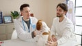 Two men examining dog cleaning ears at veterinary clinic