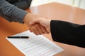 Two men sitting face to face, shaking hands after reaching an agreement, with a fountain pen lying on the contract Royalty Free Stock Photo