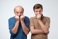 Two men covering mouth with hands in fear