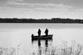 Two men fishing from a small boat on the calm water of a lake as a relaxing hobby Royalty Free Stock Photo