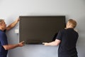 Two Men Fitting Flat Screen Television To Wall Royalty Free Stock Photo