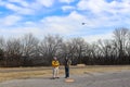 Two men flying a DJI Spark with a controller in the winter - landing pad on ground in front of them Tulsa, Oklahoma USA 12 - 28 -