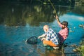 Two men friends fishing. Flyfishing angler makes cast, standing in river water. Old and young fisherman. Catching trout Royalty Free Stock Photo