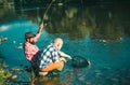 Two men friends fishing. Flyfishing angler makes cast, standing in river water. Old and young fisherman. Catching trout Royalty Free Stock Photo