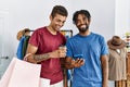 Two men friends holding shopping bags using smartphone at clothing store Royalty Free Stock Photo