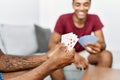 Two men friends playing poker cards sitting on sofa at home Royalty Free Stock Photo