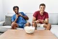 Two men friends playing video game sitting on sofa at home Royalty Free Stock Photo