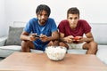 Two men friends playing video game sitting on sofa at home Royalty Free Stock Photo