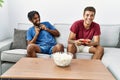 Two men friends playing video game sitting on sofa at home Royalty Free Stock Photo