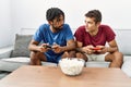 Two men friends playing video game sitting on sofa at home Royalty Free Stock Photo