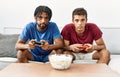 Two men friends playing video game sitting on sofa at home Royalty Free Stock Photo