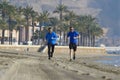 Two men friends running together on beach sand coast mountain bachground in healthy lifestyle concept Royalty Free Stock Photo