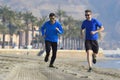 Two men friends running together on beach sand with palm trees m Royalty Free Stock Photo