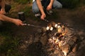 Two men are frying marshmallows over a fire in the forest. men are resting in the forest. hiking in the mountains