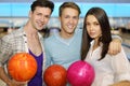 Two men and girl hold balls in bowling club Royalty Free Stock Photo