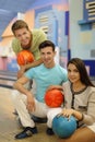 Two men and girl hold balls in bowling club Royalty Free Stock Photo