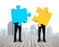 Two men holding puzzles on wooden floor Royalty Free Stock Photo