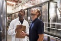 Two men inspecting vats in a modern winemaking factory