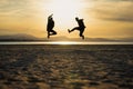 Two men jumping on the beach at sunset Royalty Free Stock Photo