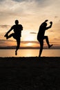 Two men jumping on the beach at sunset Royalty Free Stock Photo