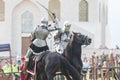 Two men knights riding horses on the battlefield and having a fight - people watching behind the fence Royalty Free Stock Photo