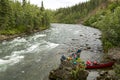 Two men launch canoes beside Alaskan river rapids Royalty Free Stock Photo