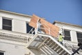 Two Men lifting a large sheet of plywood up a set of stairs